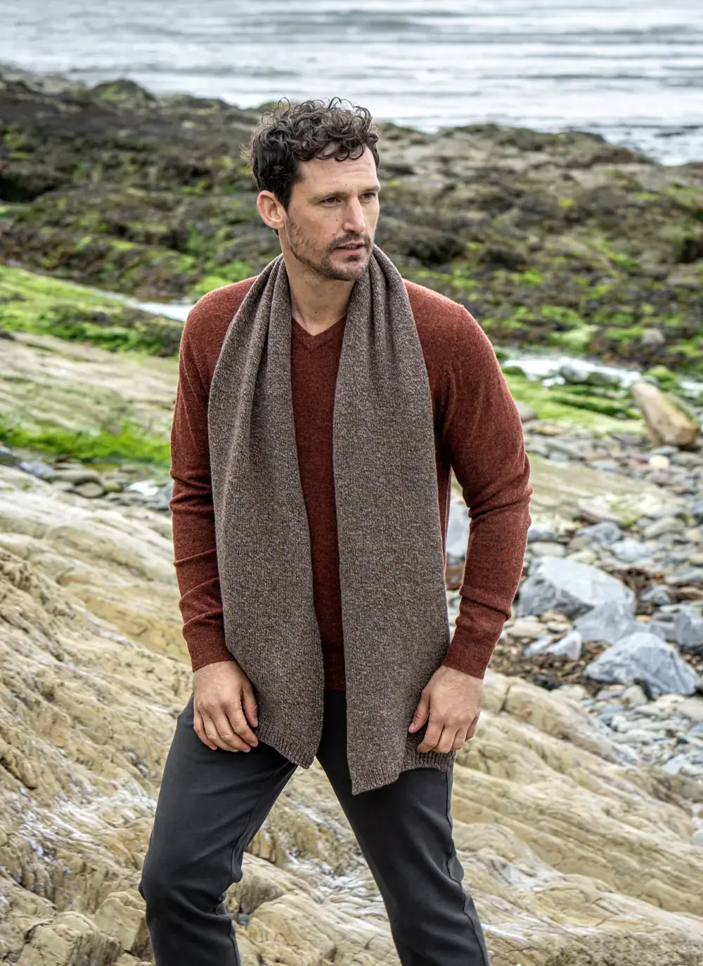 Personalized cashmere wool scarf in hazel brown, made in Ireland, styled with rust sweater and coastal backdrop